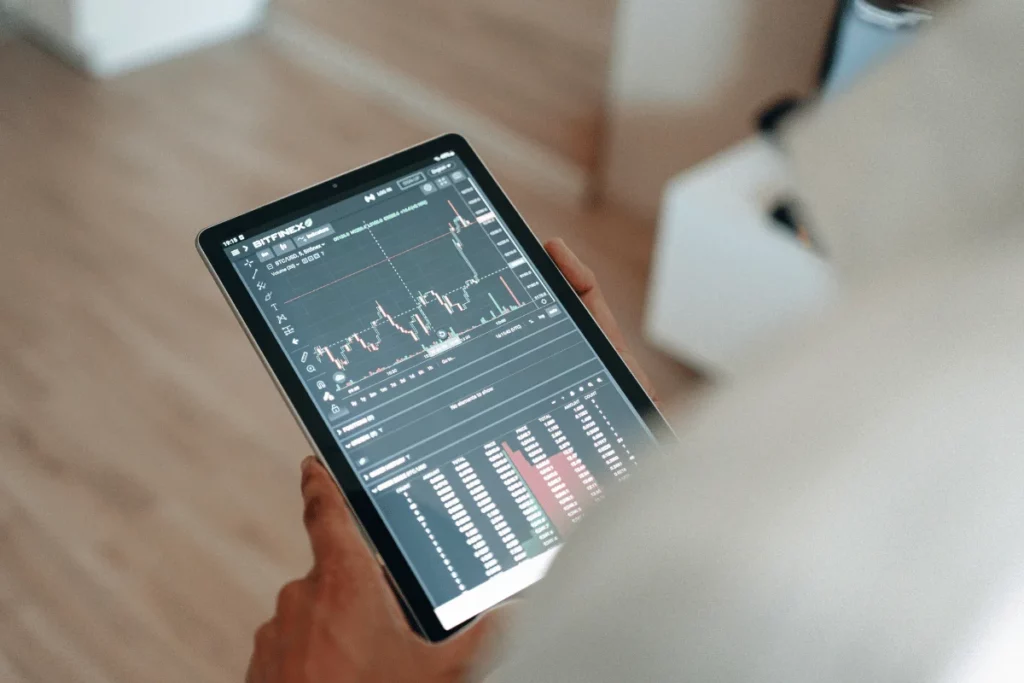 Person holding a tablet displaying stock market graphs and data.