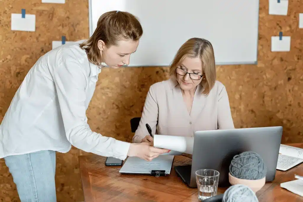 Two professionals collaborating over a document in a creative office space.