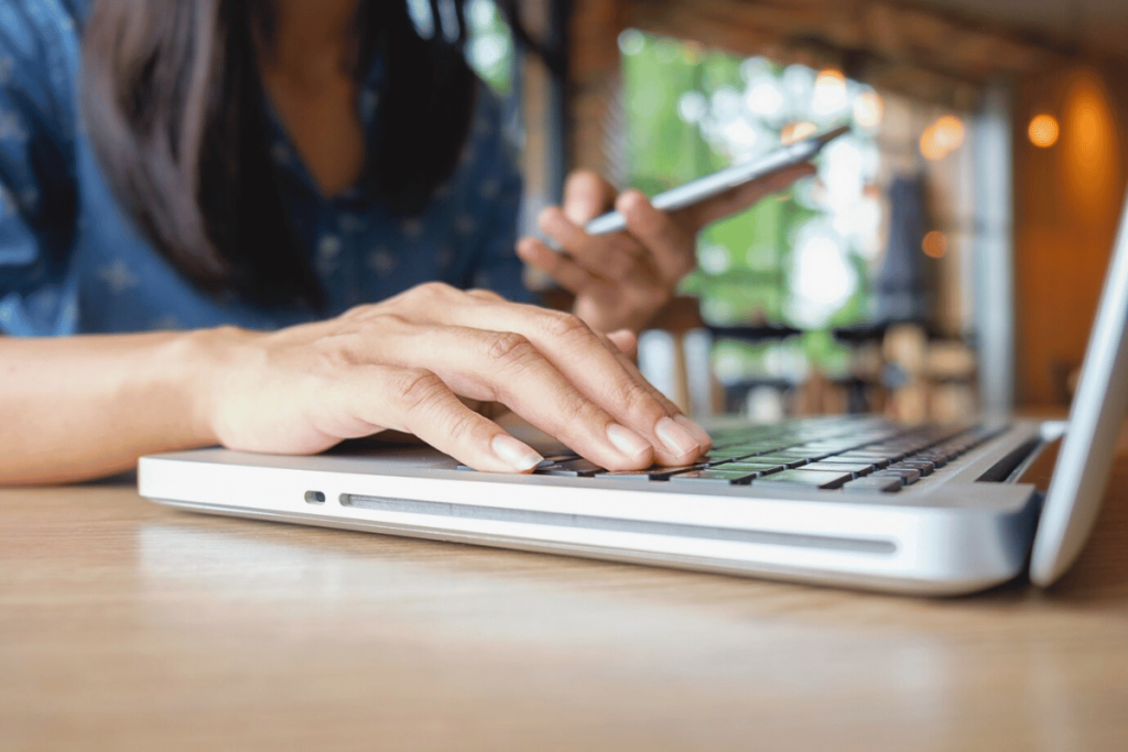 TrioSEO - A person typing on their laptop while sitting at a table.