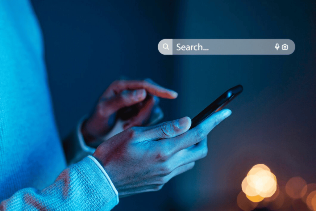 TrioSEO - A person is using their smartphone to search for something on the internet at night.