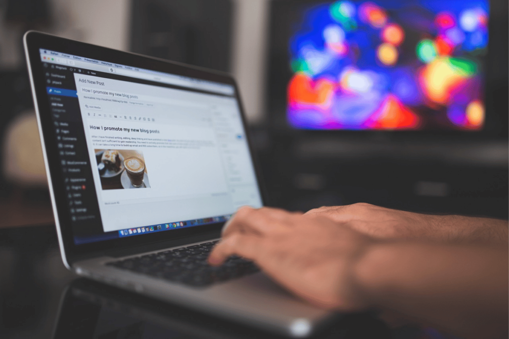 Blogger crafting a new post on WordPress with a vibrant abstract background on monitor.