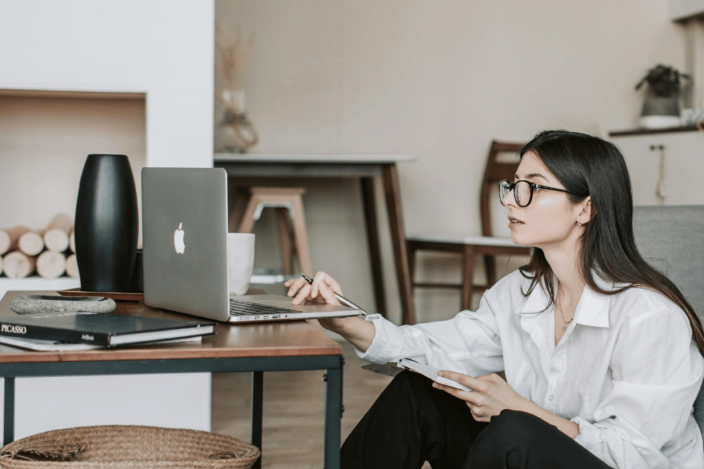 Professional woman with glasses working on a MacBook at a minimalist desk.