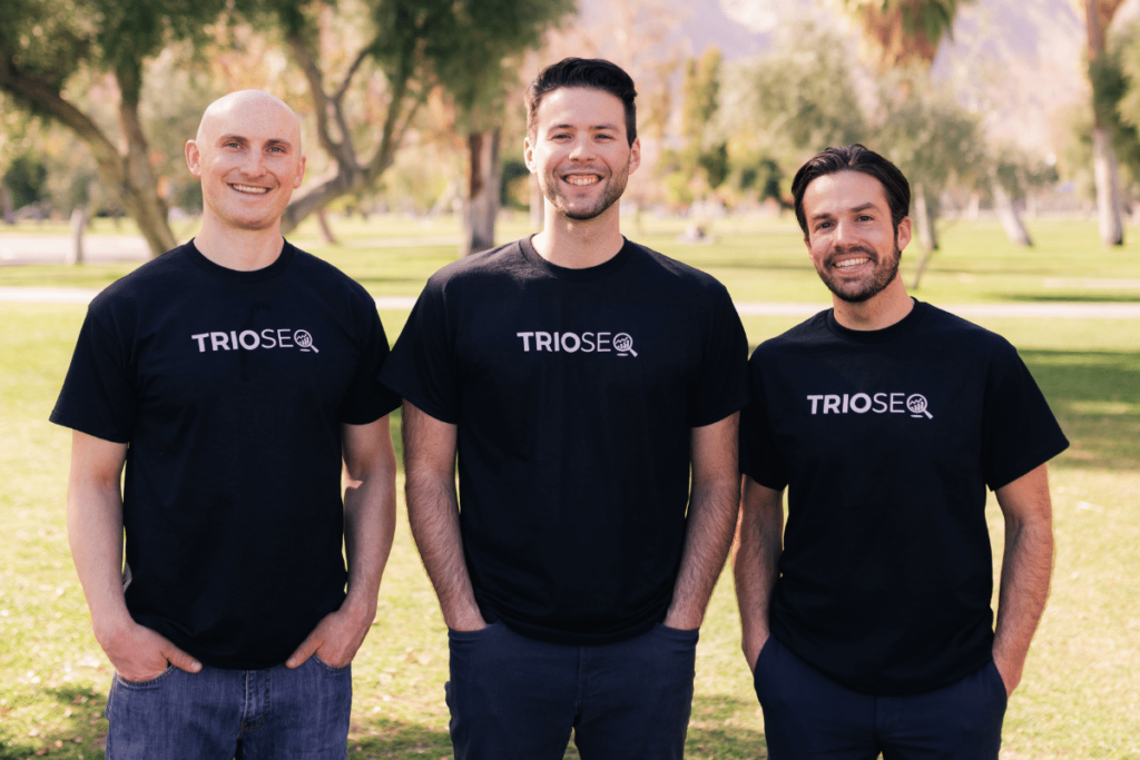 Nathan, Steven, Connor wearing TRIOS® t-shirts, smiling outdoors with palm trees.