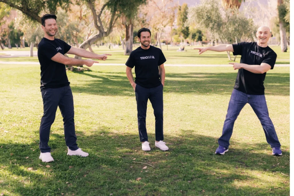 Smiling trio Steven, Connor, and Nathan model black TRIOS® t-shirts outside.