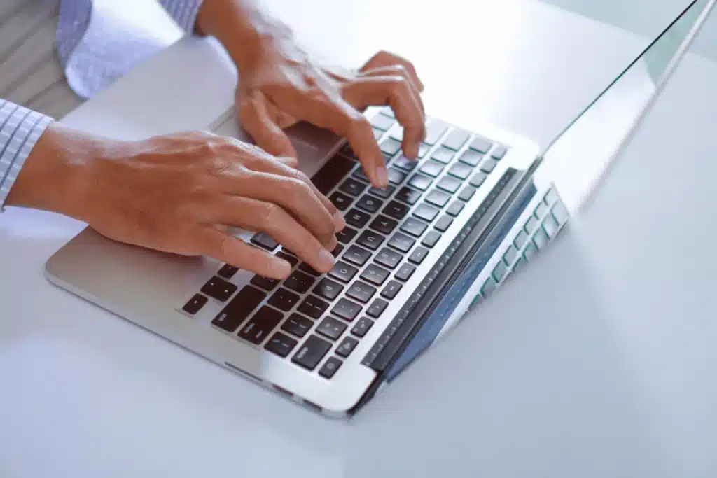 Close-up of hands typing on a laptop keyboard.
