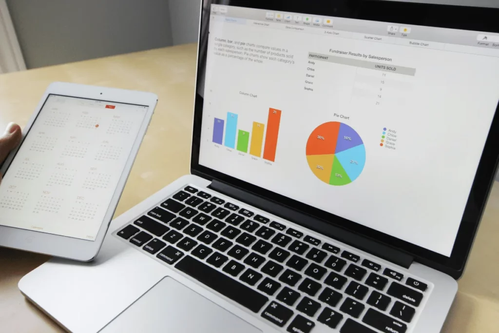 Person reviewing charts and calendar on laptop and tablet.