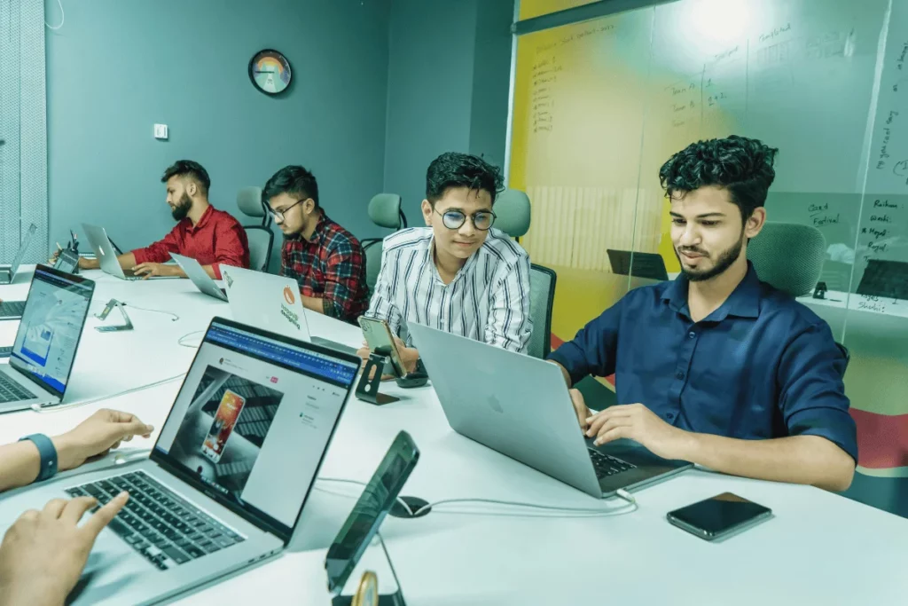 Team member in a creative shirt using a laptop during a meeting.