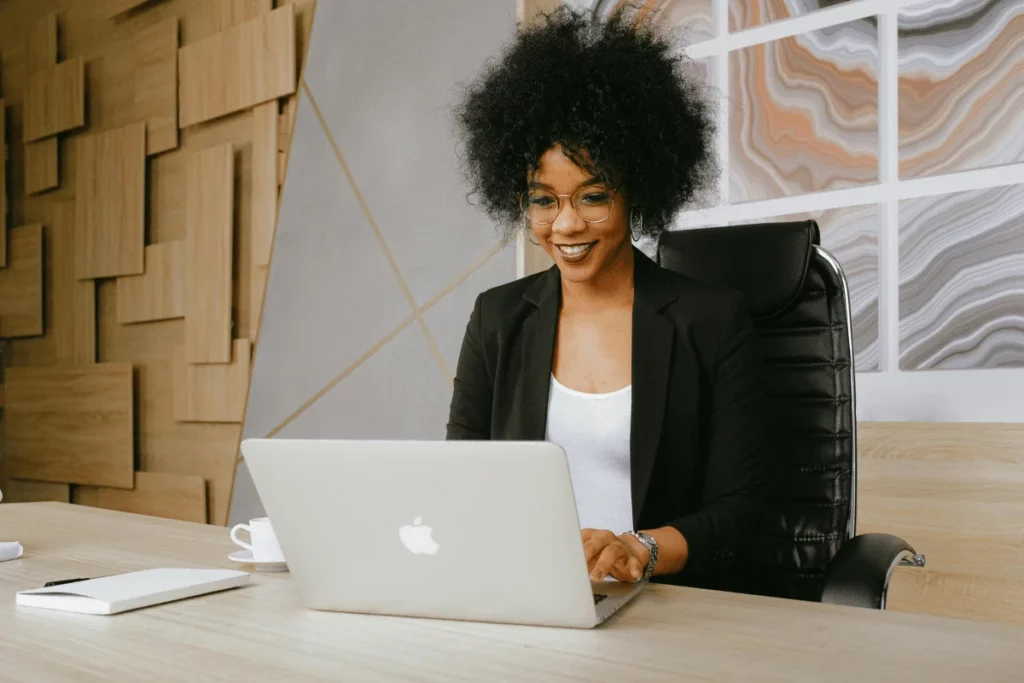 Happy businesswoman typing on her laptop in a stylish workspace.