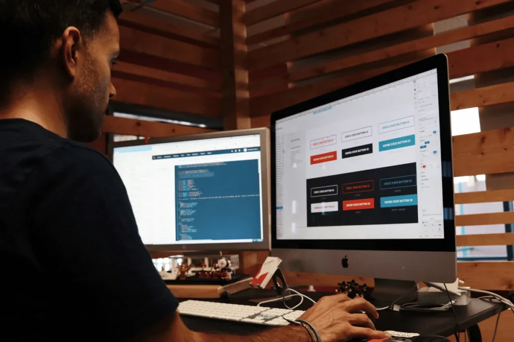Software engineer coding on a dual-screen setup in a home office.