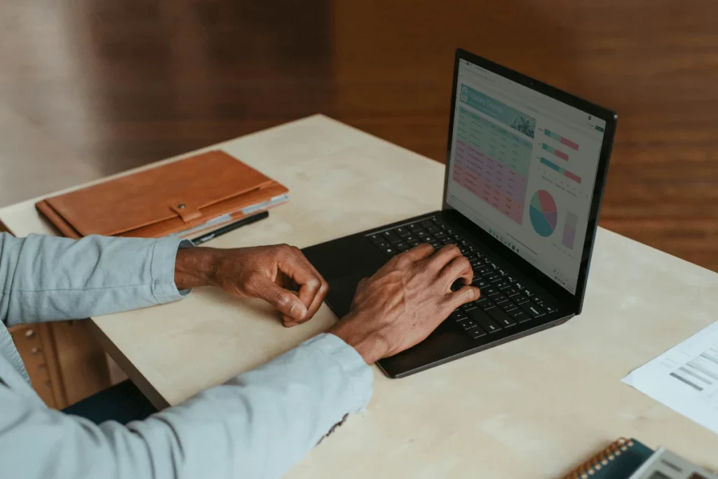 Hands typing on a laptop, analyzing performance metrics.