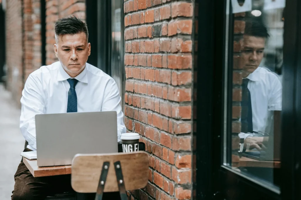 Person in a white shirt and tie using a laptop at a café.