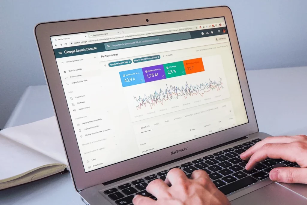 Close-up of hands on a MacBook keyboard with Google Search Console statistics.