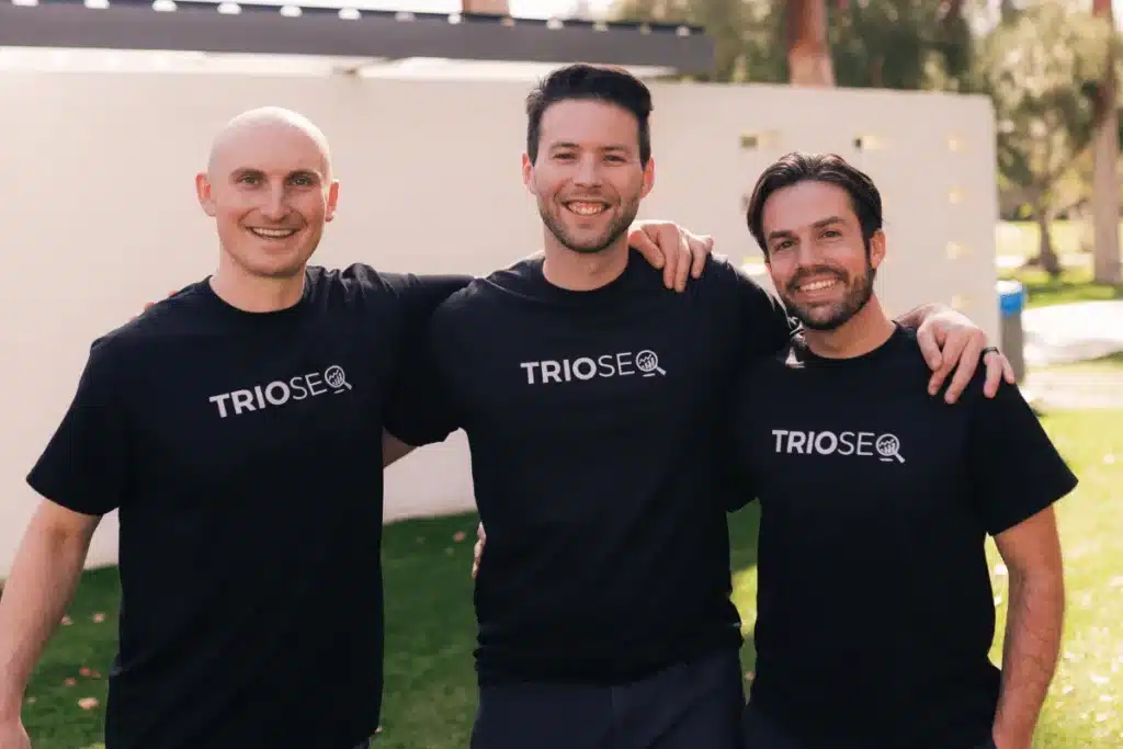 Nathan, Steven and Connor smiling outdoors, wearing branded black shirts, symbolizing teamwork and SEO expertise in digital marketing.