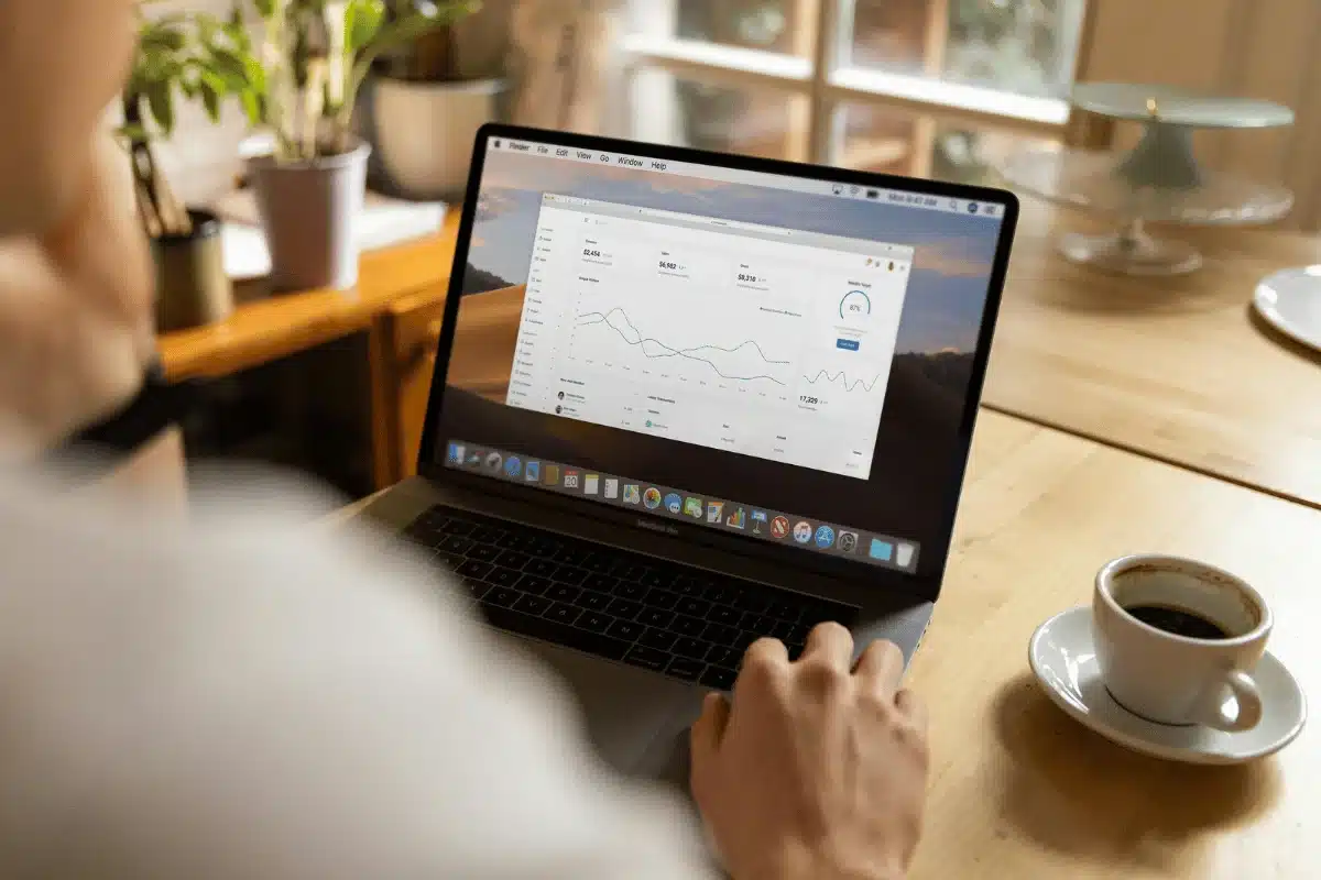 Worker checking analytics on a laptop with a cup of coffee.