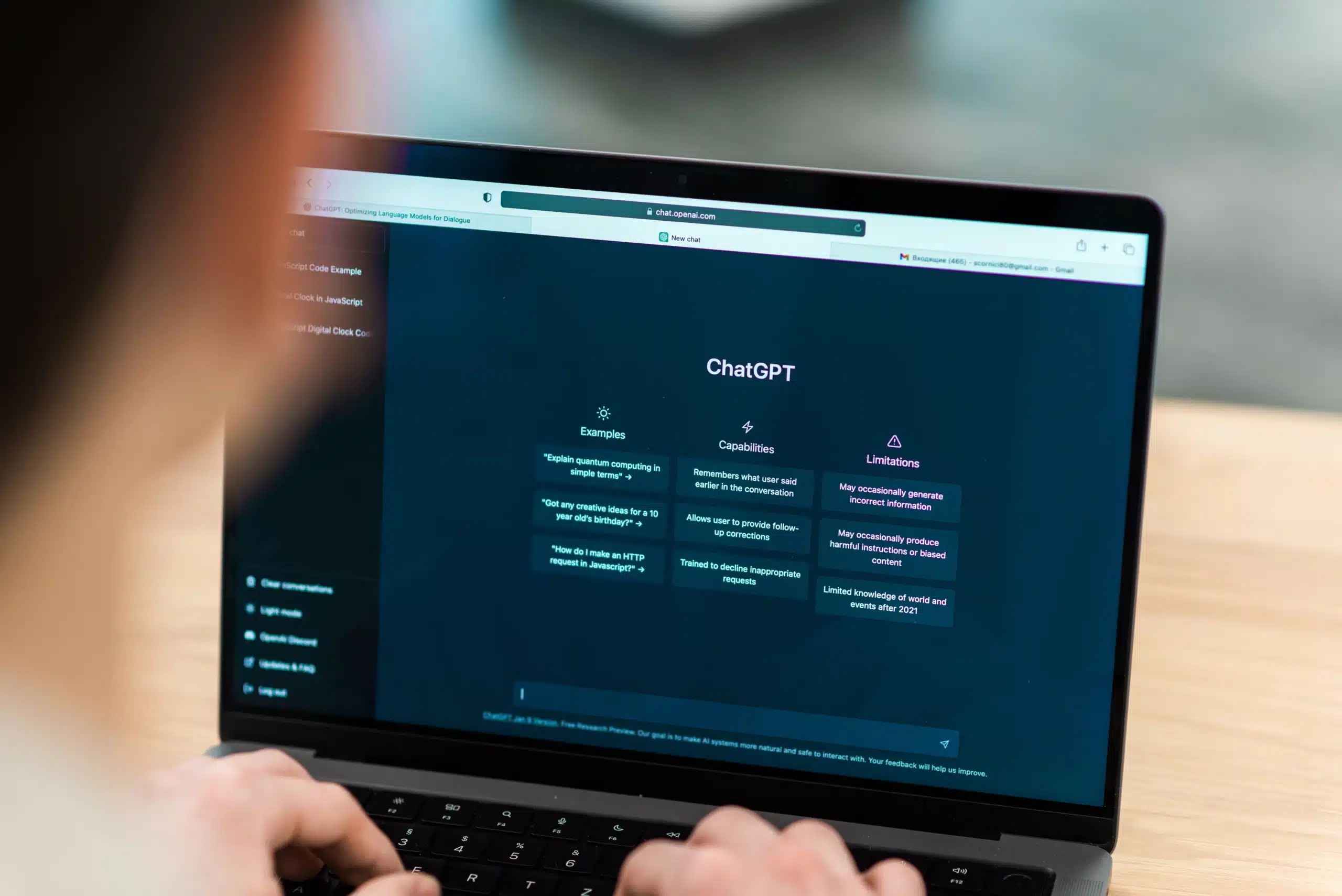 A person interacts with ChatGPT on a laptop screen, displaying examples, capabilities, and limitations of the AI tool.